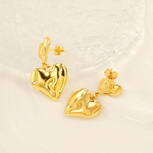 Elegant gold double heart drop earrings with irregular lava texture on glass plate