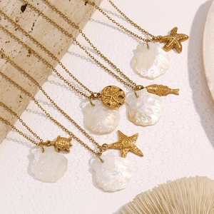 Flat lay of gold starfish and shell necklaces on a beach style textured background