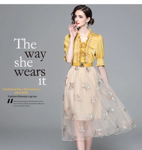 Detail of a two-piece dress with yellow satin top and butterfly embroidered tulle skirt