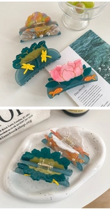 Detailed close-up of acetate hair claws featuring seashell pearl and goldfish designs