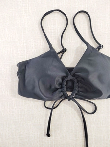 Detail of black bikini top featuring O-ring ruching and crossed tie-back straps design