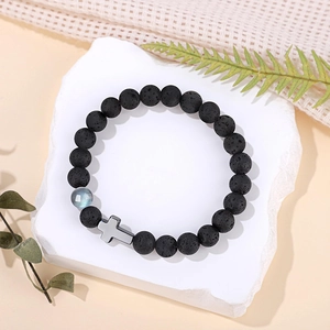 Gros plan d'un bracelet en pierre de lave 8mm avec perle de lune et breloque croix