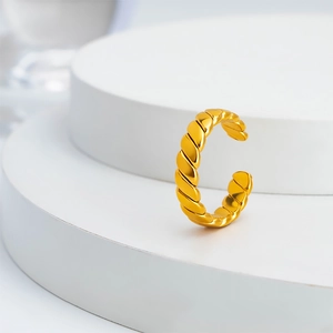 Minimalist gold wheat twist ring on a white pedestal with polished titanium steel finish