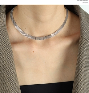 Detail of silver mesh choker necklace on model wearing a brown textured suit jacket