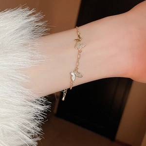 Close-up of gold butterfly bracelet with zircons and shells on a model's wrist