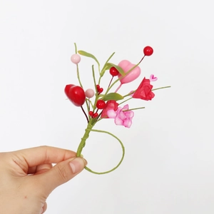 Close-up of pink and red heart-shaped floral napkin ring with green stems and berries