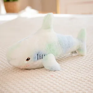 Colorful gradient shark plush toy in soft blue and green tones on a knit background