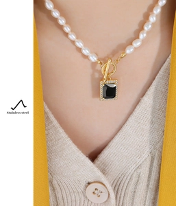 Detail of freshwater pearl necklace with black gemstone pendant and gold T-bar clasp