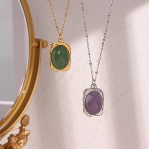 Detail of vintage oval stone pendants in green and purple with embossed metal textures
