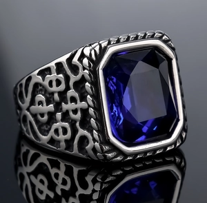 Macro shot of retro stainless steel ring with deep blue gemstone and embossed texture