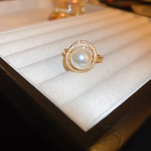 Detailed macro shot of a pearl ring with micro-pave diamonds in a white velvet box