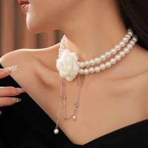 Detail of double-layer pearl necklace featuring a white plush flower and silver tassels
