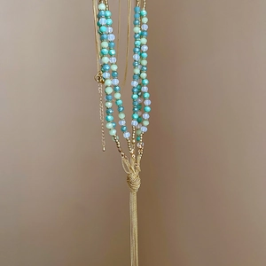 Detail of multi-layer turquoise bead necklace with elegant gold chain tassels and knots