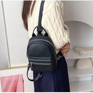 Detail of black lychee grain leather mini backpack showing metallic silver zipper and strap