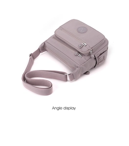Detail view of a light purple nylon crossbody bag with multiple zip compartments