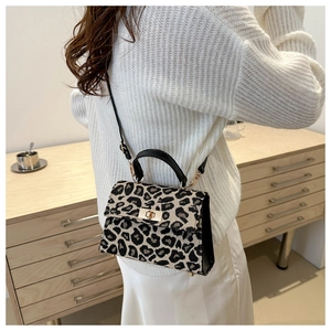 Detail of leopard print crossbody bag with gold twist lock and protective metal feet