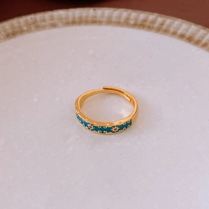 Gros plan sur une bague ajustable dorée avec émail bleu sarcelle et motifs de soleil