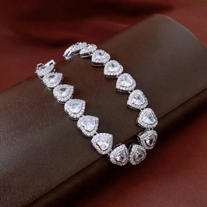 Close-up of heart-shaped silver bracelet with sparkling zircon stones on leather stand