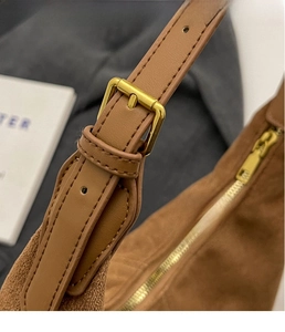 Detailed close-up of premium gold buckle and stitching on brown frosted leather tote bag
