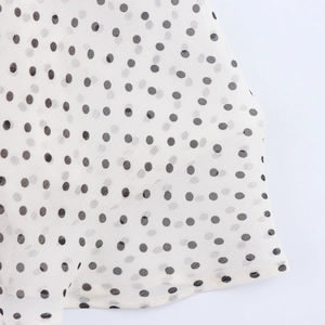 Close-up of lightweight white chiffon fabric with black polka dots and soft texture