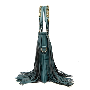 Detail view of the side fringes and gold woven handle on the dark green leather handbag