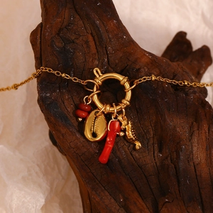 Detail of 18K gold plated ocean charm bracelet with red coral, seashell and seahorse