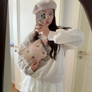 Detail of beige corduroy pouch with cute bear patterns held by a model in soft lighting