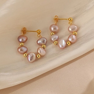 Macro detail of baroque pearls earrings on champagne silk background fabric