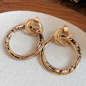 Macro shot of layered gold hoop earrings featuring stylish leopard print fabric wrap