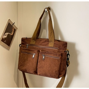 Detailed macro view of brown corduroy bag texture with zipper pockets and strap