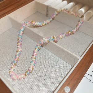 Détail d'un collier en perles colorées fait main sur un support en lin