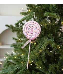 Close-up of pink and white plush lollipop ornament hanging on a Christmas tree branch