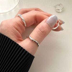 Close-up of minimalist wave pattern 925 sterling silver ring on hand with metallic luster
