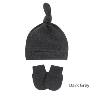 Detail of dark grey knitted baby hat with top knot and matching anti-scratch mittens