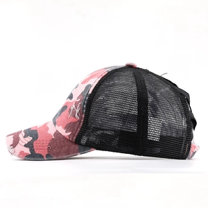 Detail of pink camo trucker hat with pony-tail hole and distressed brim on white background