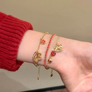 Detailed close-up of a three-piece gold-plated bracelet set with a rocking horse and red gem