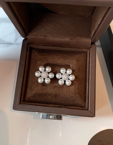 Détail de boucles d'oreilles fleur en perles avec zircons dans un écrin de bijoux