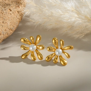 Vintage gold flower earrings with white pearls on a stone and feather backdrop