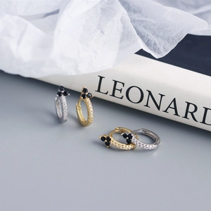 Macro view of flower-shaped earrings with black zircons in gold and silver finishes