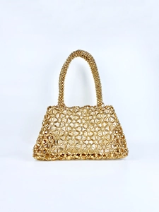 Detailansicht einer hohl gewebten goldfarbenen Perlenhandtasche mit Metallic-Glanz