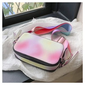 Close-up of rainbow gradient crossbody bag with wide strap on a white fabric background