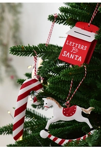 Close-up of vintage iron Santa letter mailbox and candy cane hanging on a Christmas tree