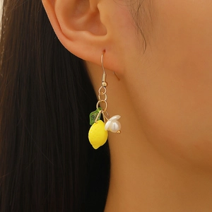 Close-up of yellow lemon pendant earrings with green leaf and white pearl charm