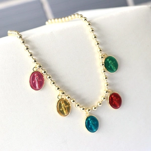 Detailed macro view of gold beaded chain with colorful enamel religious icon charms