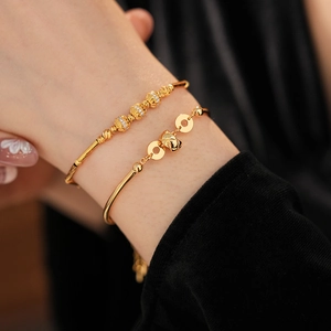 Detail of 18K gold-plated bamboo-style bracelet with cubic zirconia and small bell charm