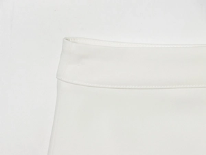 Detailed close-up of white woven fabric texture and stitching on a waist blazer dress