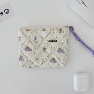 Close-up of floral quilted coin purse with rabbit pattern and purple wrist strap