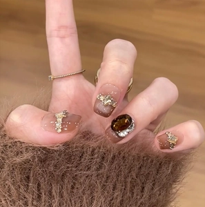 Detail of light brown cat-eye gradient press-on nails with sparkling rhinestones and amber gems
