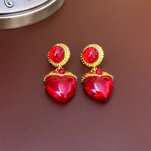Macro detail of vintage red heart-shaped gemstone earrings on brown leather background