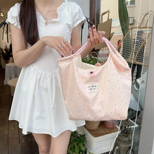 Detail of pink floral canvas tote bag with rabbit patterns and woven handles